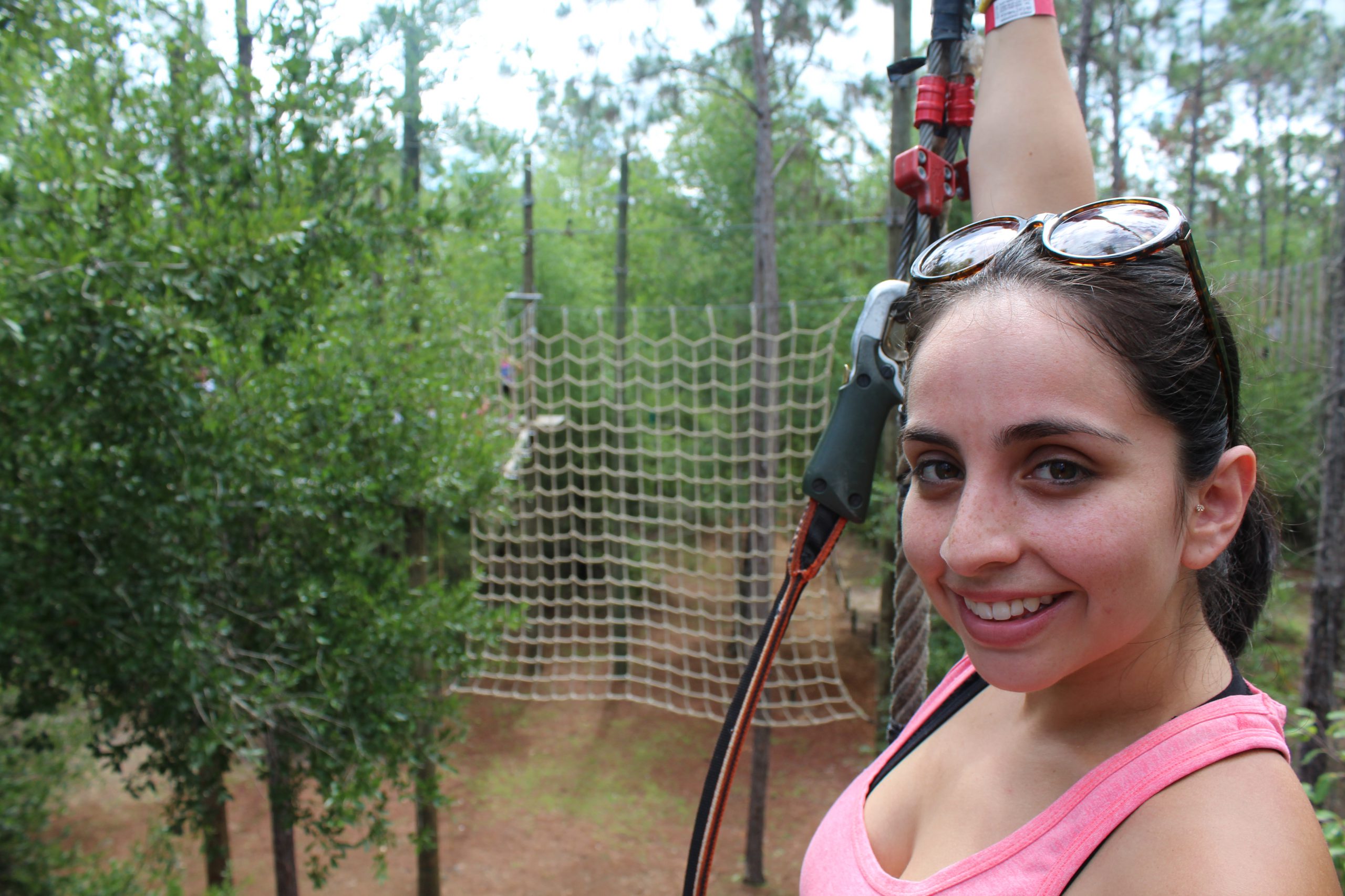 Guest smiling while climbing the ropes course at Orlando Tree Trek.