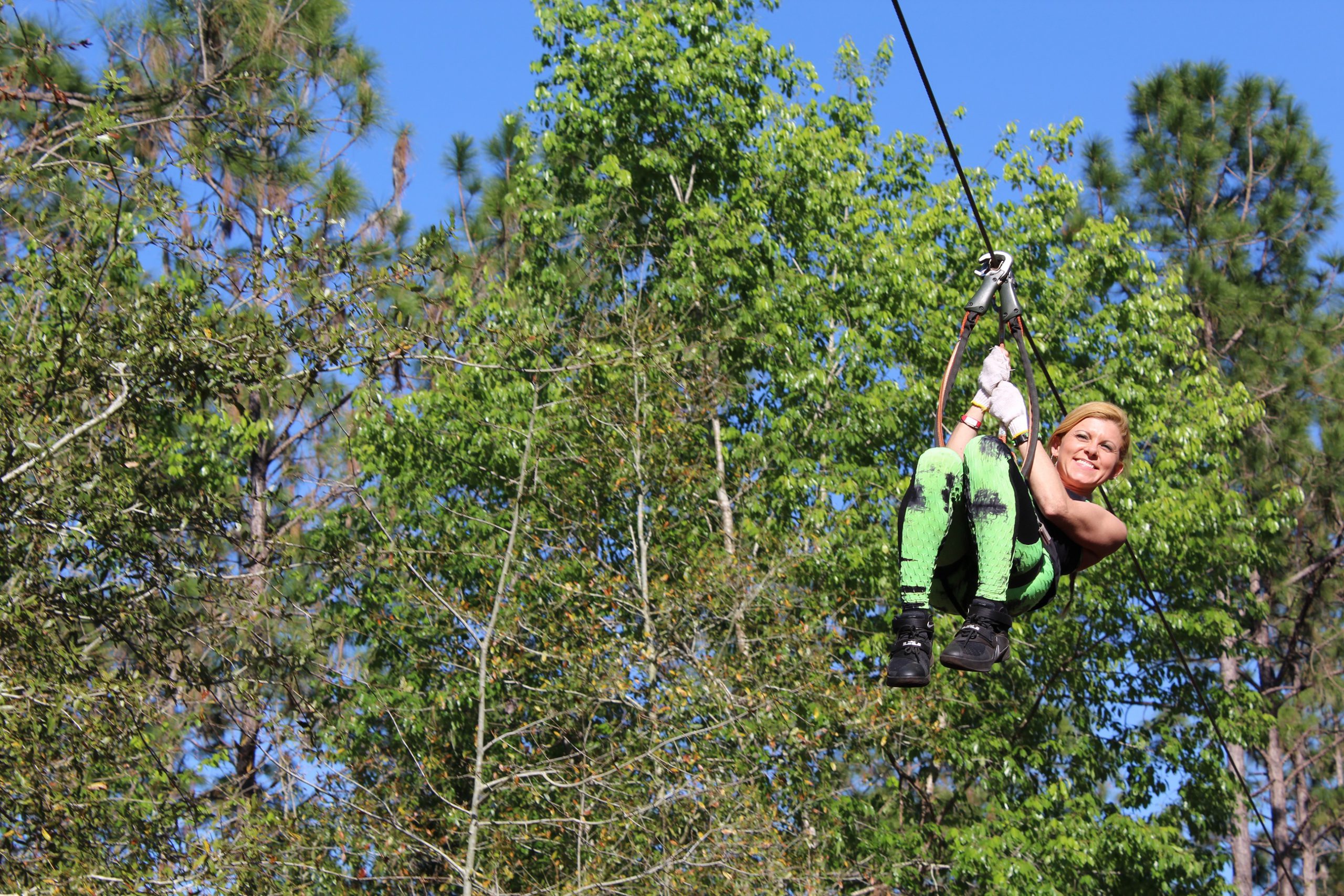a guest ziplines through the treetops at Tree Trek.