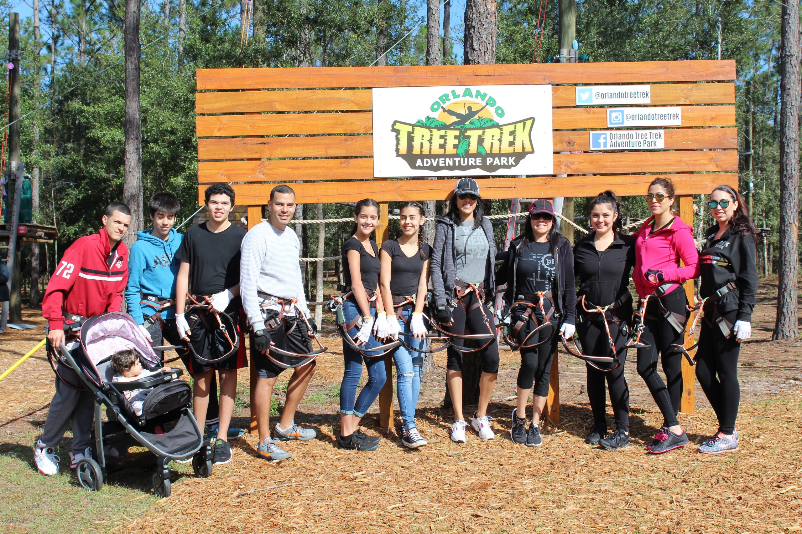 A family is gathered around a sign at Orlando Tree Trek.